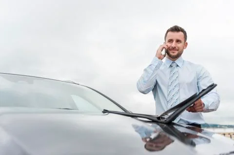 Businessman with documents on cell phone at car Stock Photos