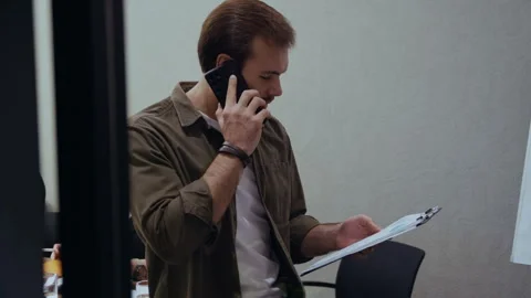 Businessman with Documents Having a Phone Conversation Beside Wooden Table Stock-Footage 321017542