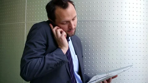Businessman with documents talking on cellphone, steadicam shot HD Stock-Footage 10760870