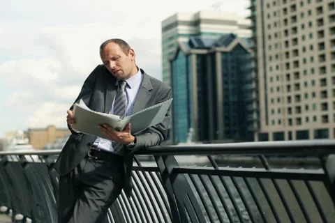 Businessman with documents talking on mobile phone in the city NTSC Stock Footage 11512257