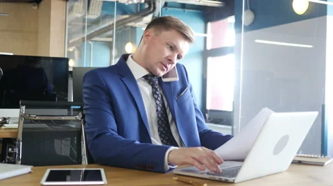Businessman doing multitasking , working with documents , laptop and phone Stock Footage 64709869