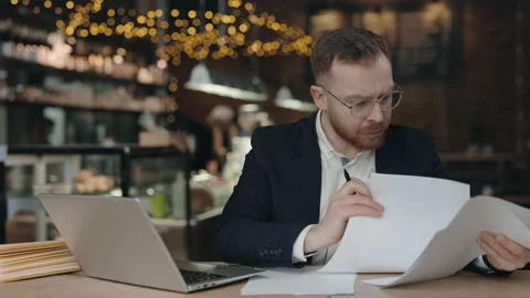 Businessman doing paperwork. Man looking through work paper while sitting. Stock Footage 182506465