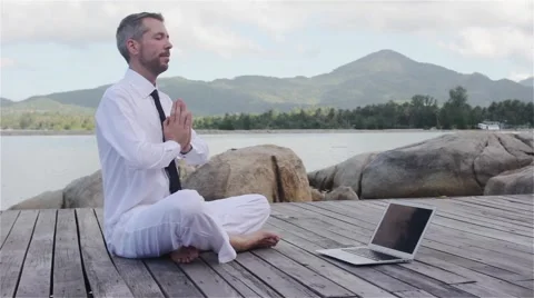 Businessman doing yoga on a wooden bridge with a laptop 動画素材 59369532