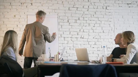 Businessman is drawing a graph and discussing it with his business partners in Stock Footage 90490918