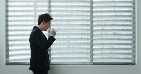 Businessman drinking coffee and looking out the window Stock Footage 100950547