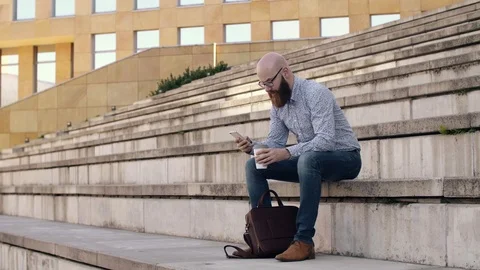 Businessman drinking coffee and using mobile phone outdoors 動画素材 90946812