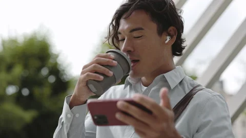 Businessman drinking coffee and using mobile outdoors Stock Footage 165588362