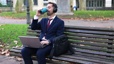 Businessman drinking coffee and working on laptop in park during autumn in .. Stock Footage 293483424