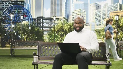 Businessman drinking coffee cup while using laptop on park bench Stock Photos