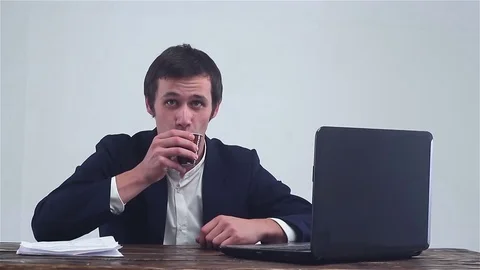 Businessman drinking coffee, looking at the camera and working on a laptop. Stock Footage 72992970