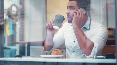 Businessman drinking coffee by the window in the cafe, and calling with phone Stock Footage 73993060