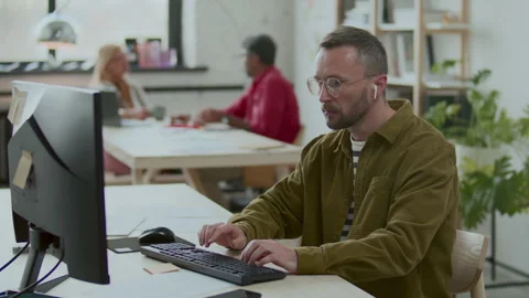 Businessman in Earphones Using Computer and Taking Notes at Office Desk Stock Footage 292939529