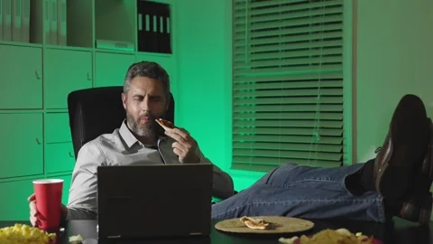 Businessman eating snacks while working late in office. Man with chips in front Stock Footage 343603944