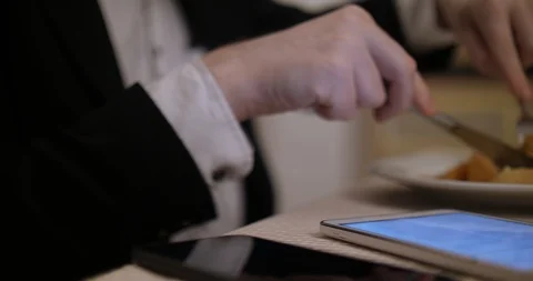 Businessman eats at a restaurant and uses a tablet Closeup Vidéo 88058061