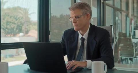 A businessman ending a phone call while working on a laptop at the office. Stock Footage 140182146