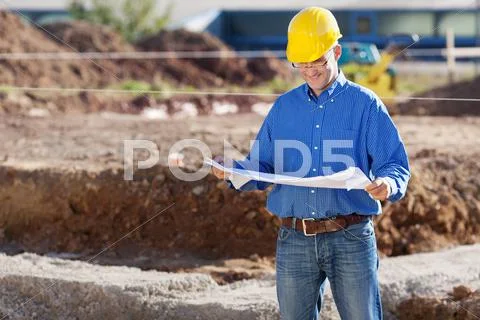 Businessman examining blueprint at construction site Stock Photos