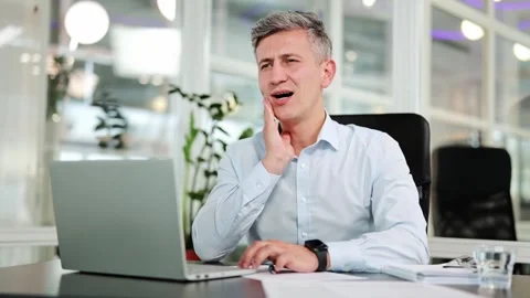 Businessman Experiences Tooth Pain While Working on Laptop in Modern Office Stock-Footage 312370470
