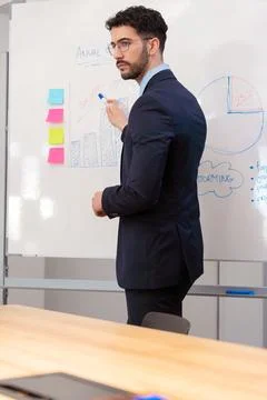 Businessman explaining growth chart during annual meeting at whiteboard.Vertical Stock-Fotos