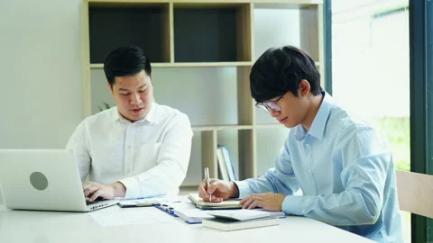 Businessman explaining numeric graphs on computer to colleagues. 库存影片 213462761