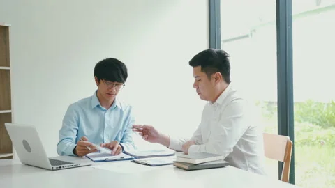 Businessman explaining numeric graphs on computer to colleagues. 库存影片 213462983