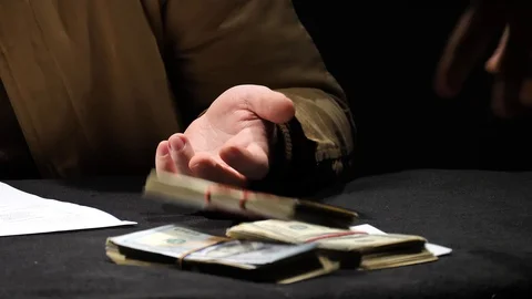 A businessman is explaining something while a pack of dollars is laid. Vídeo Stock 129786644