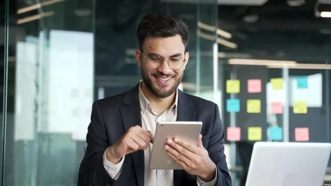 Businessman in formal suit is using browsing digital tablet sitting at workplace Stock Footage 300782773