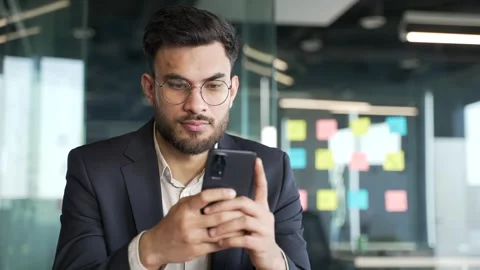 Businessman in a formal suit is using browsing mobile phone at workplace  Stock-Footage 343355288