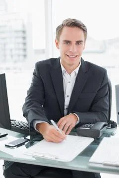 Businessman in front of computer writing document at office desk Foto stock