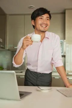 Businessman in front of his computer drinking coffee at home Stock Photos