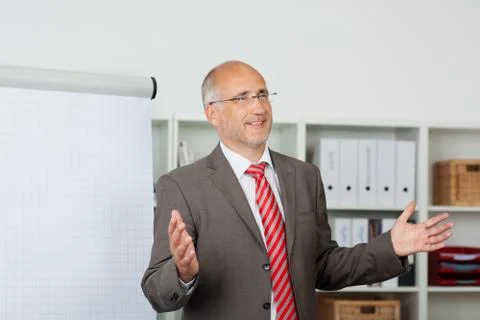 Businessman gesturing while giving presentation in office Stock Photos