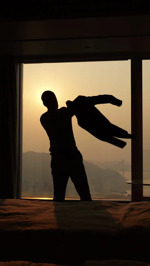 Businessman getting dressed in a suit, silhouetted slow-mo at sunset Vidéo 341004592