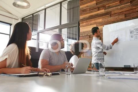 Businessman giving creative presentation to his colleagues Stock Photos