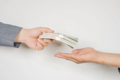 Businessman giving or paying stack of dollars banknote to a man over white .. Stock Photos