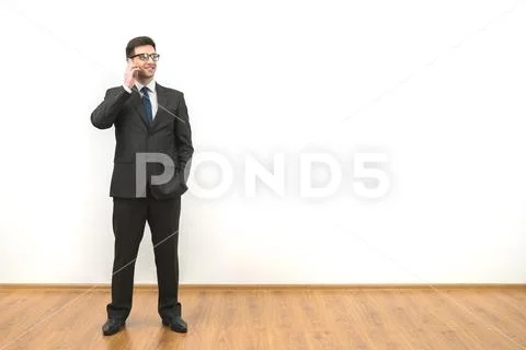 The businessman with glasses phones on the white wall background Stock Photos
