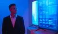 The businessman in glasses standing near big displays with graphs Photo