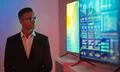 The businessman in glasses standing near big displays with graphs Photo