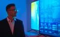 The businessman in glasses standing near big displays with graphs Photo