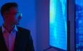 The businessman in glasses standing near screens with graphs Photo