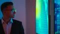 The businessman in glasses standing near screens with graphs Photo