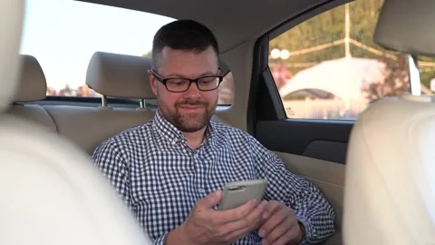 Businessman with glasses using smartphone in back seat of luxury car Stock Footage 204942255