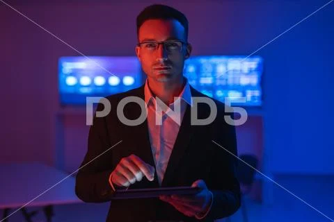 The businessman in glasses working with a tablet in the dark room Stock Photos