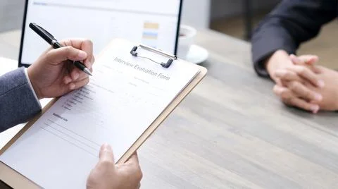 Businessman hand checking the interview evaluation paper for job interview at Stock-Fotos