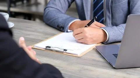 Businessman hand checking the interview evaluation paper for job interview at Stock Photos