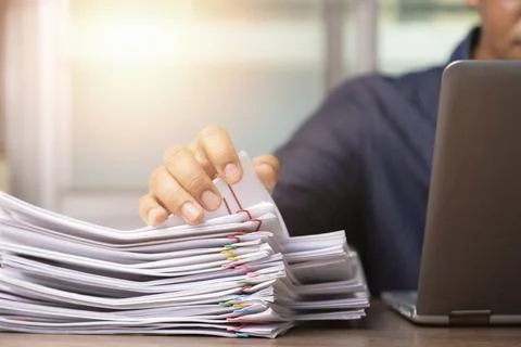 Businessman hand pick up Stack overload documents report paper with colorful Stock Photos