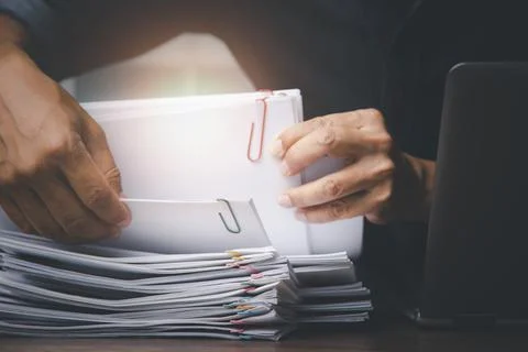 Businessman hand pick up Stack overload documents report papers with colorful Stock Photos