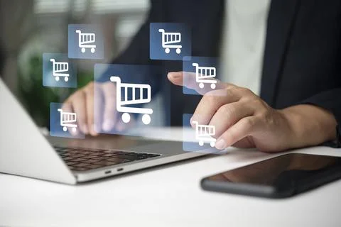 Businessman hand touching virtual screen with shopping cart icons on laptop.. Stock Photos