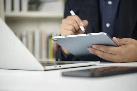Businessman hand using digital tablet stylus pen writing screen office desk.. Stock Photos