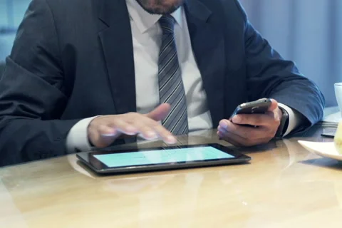 Businessman hands comparing data on tablet computer and smartphone by table NTSC Stock Footage 57535338