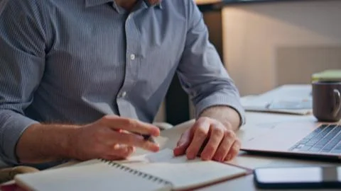 Businessman hands making notes at notebook indoors closeup. Tired man pondering Stock Photos