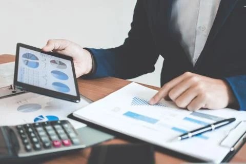 Businessman hands using text information on digital tablet to analyze financi Stock Photos
